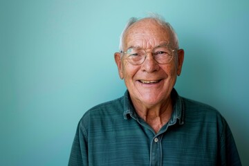 Portrait of a glad caucasian man in his 70s smiling at the camera isolated on soft teal background