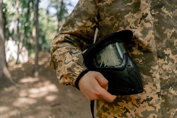 in the forest player for playing pintball a young guy ready for competition stands with a mask in...