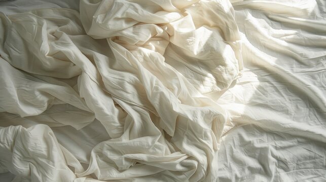 Top down view of white sheets and rumpled blanket on a bed in the morning