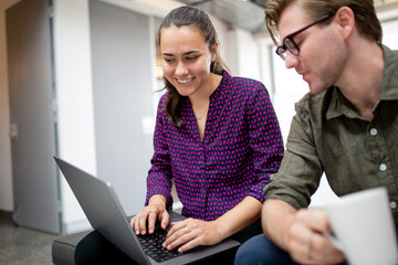 Two businesspeople with a laptop discussing project