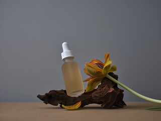 Empty bottle of skincare product, serum on gray background with wooden deco. Creative still life...