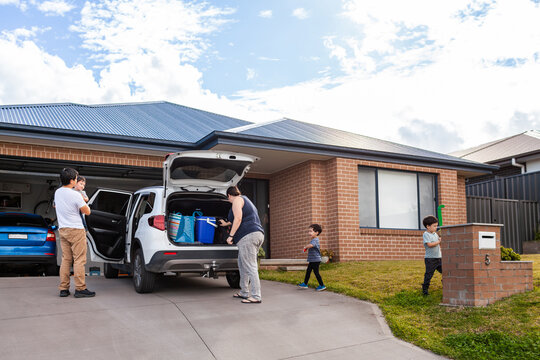 Aussie family packing car for Saturday sports outing kids playing in front yard