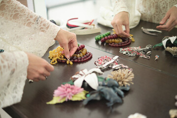 A person arranges colorful beaded necklaces and jewelry on a table. This image showcases the beauty and variety of handcrafted accessories.