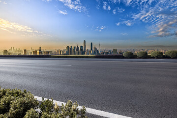 Empty asphalt road and cityscape in modern city at sunset