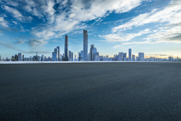 Empty asphalt road and cityscape in modern city at sunset