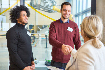 Two professionals greeting a woman at a robotics training session