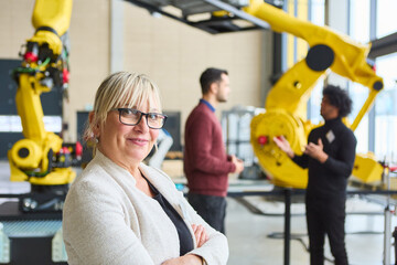 Confident woman in robotics laboratory with colleagues discussing automation processes