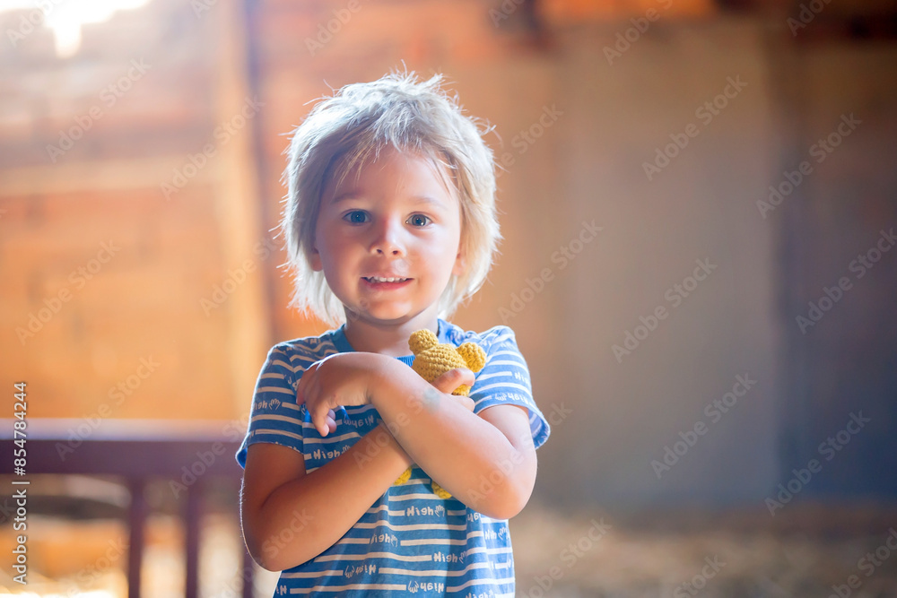 Poster Little toddler blond boy, holding little knitted teddy bear, looking sad