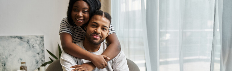 Obraz premium A couple embraces in their home, looking lovingly at the camera.