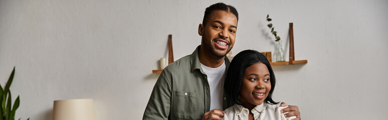 A happy African American couple smiles for the camera in their home.