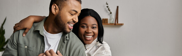 An African American couple embraces warmly in their home, laughing and enjoying each others company.