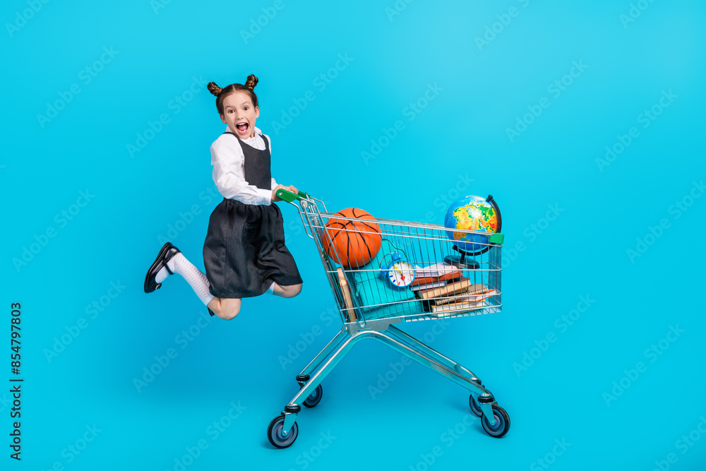 Canvas Prints Full body photo of cute little girl push jump shopping cart black friday dressed stylish school uniform isolated on blue color background