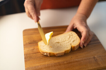 young female hands spreading butter on bread, closeup shot