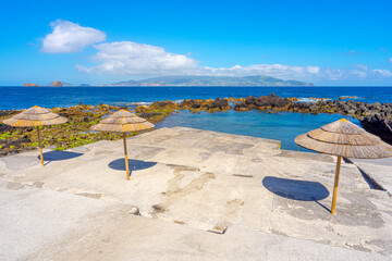 Barca bathing area with natural pools and straw umbrellas. Pico Island in the Azores archipelago.