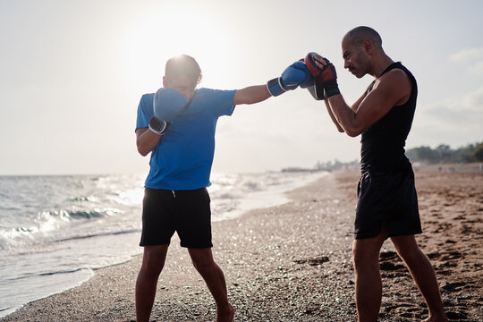 Teenage boy fighter training with his father on the sea shore.