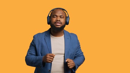Joyous person having fun, listening upbeat songs through headphones, feeling immersed. Jolly BIPOC...