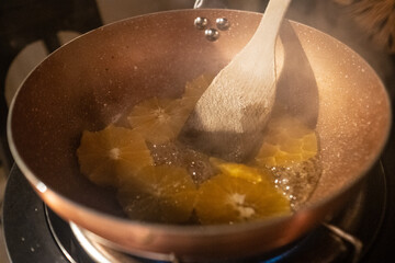 Stirring Orange Slices in Copper Pan on Stove