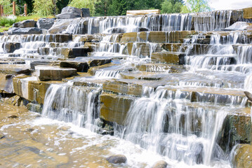 Cascade of artificial waterfalls on a water staircase on the riverbed. Long exposure.