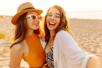 Cheerful women making selfie while having fun on the beach. Friends together. Travel, blogging, weekend, relax and lifestyle concept.