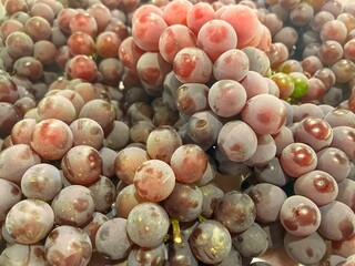 Pile of fresh brazilian pink grapes on  market stall for sale.