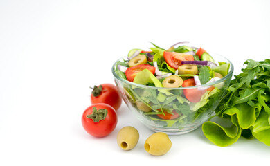 Green vegan salad from fresh vegetables, olives and tomatoes on a white background. Close-up. Copy space. Selective focus.