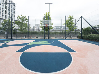 The basketball hoop on the court is under sunny weather