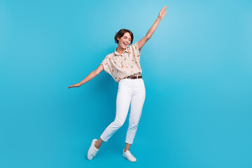 Full body photo of gorgeous positive lady raise hands have good mood dancing isolated on blue color background