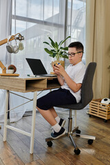 A young boy with Down syndrome sits at a desk, playing at home.