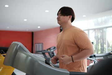 Overweight man running on treadmill in gym