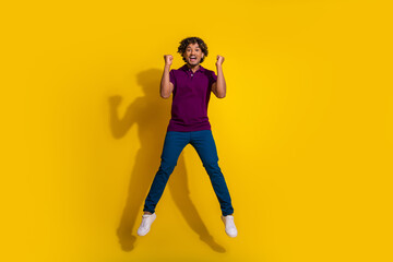 Full length photo of handsome young man jump winning dressed stylish violet garment isolated on yellow color background
