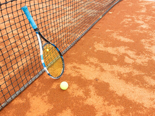 Close up view of tennis racket and ball on the clay tennis court