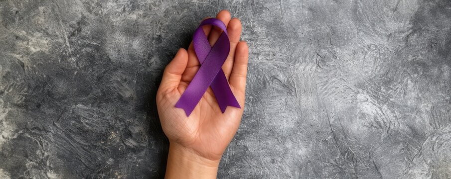 Hand holding a purple ribbon symbolizing awareness and support on a textured gray background, representing hope and solidarity.