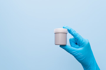 Hands in blue glove holding stool container sterile sample specimen bottle. Fecal analysis help...