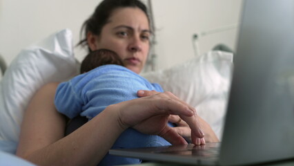 New mother in hospital bed focused on laptop with newborn baby on chest, balancing work and...