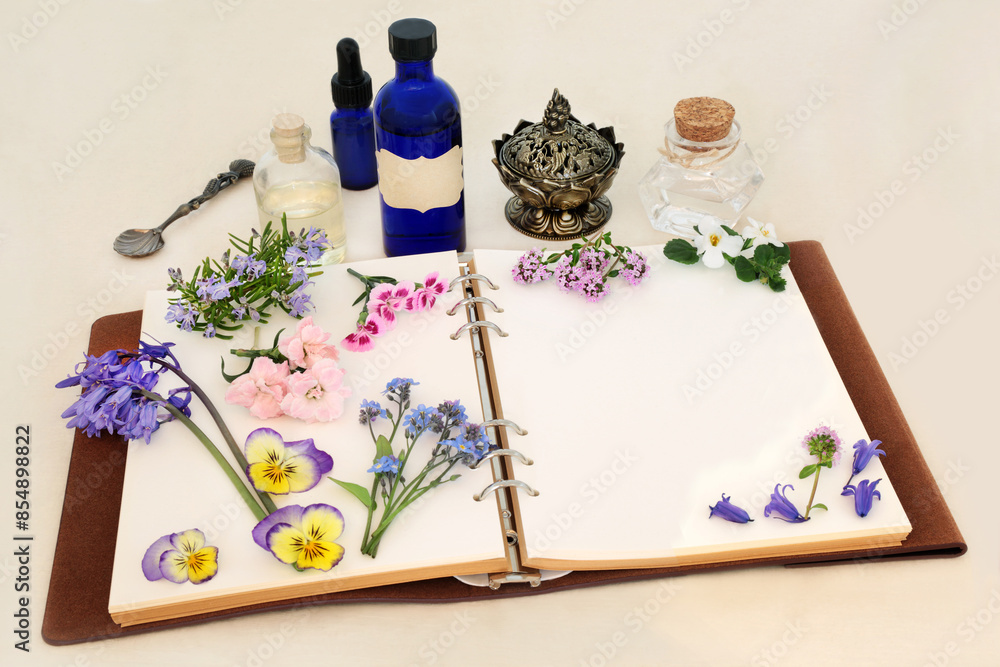 Wall mural Herbal medicine preparation with spring flowers, herbs and essential oil bottles with notebook. Natural floral nature concept for flower essences and remedies on hemp paper.