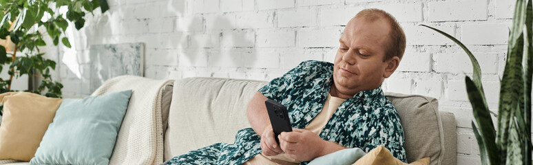 A man with inclusivity relaxes on a couch in his living room, scrolling through his phone.