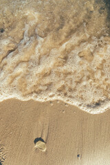 Foamy waves washing up on a sandy shore.