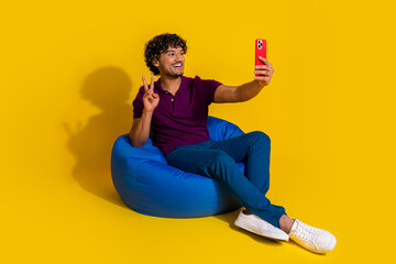 Full size photo of nice young man selfie photo v-sign sit bean bag device wear trendy violet outfit...