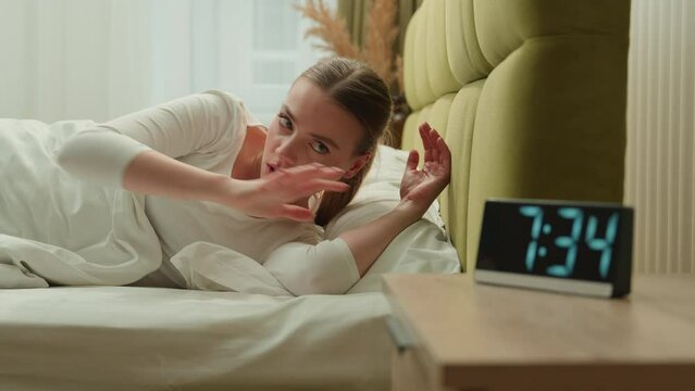 Angry annoyed girl wake up in morning bed home bedroom woman female lady anger mad furious loud sound of alarm clock awaking early hide alarmclock in closet covering pillow continue sleep insomnia