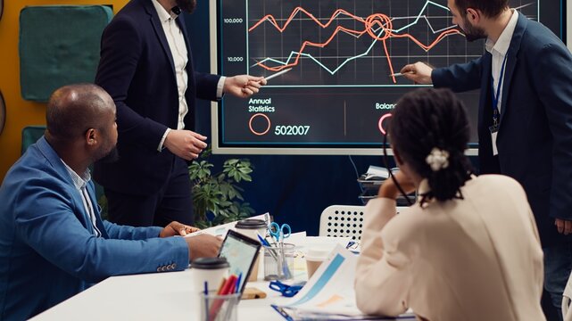 Marketing team attending a tensed meeting to review sales trends on interactive board, looking for ways to increase the organization profit and ensure global success. PR specialists. Camera A.