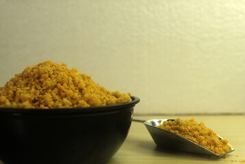 Ground bitter cassava in bowl and scoop. Traditional creole food, yuca, couac side view.
