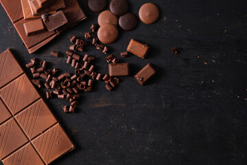 Top view of various milk and dark chocolate on black background with copy space. Dessert food background.