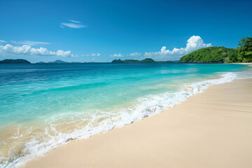Obraz premium Pristine beach with powdery white sand leading into crystal-clear turquoise waters under a bright blue sky with fluffy clouds