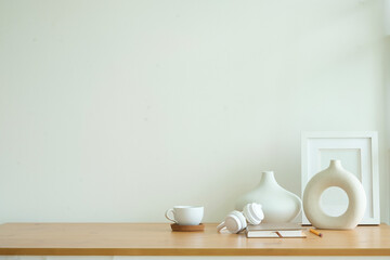 Empty picture frame on wooden  table with modern white ceramic vase.