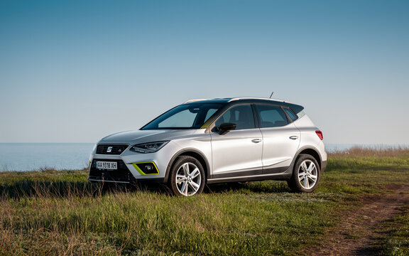 silver SEAT Arona parked on grass on a side of dirt road near the sea. Three quarter front view of spanish hatchback crossover. Odesa region, Ukraine - April 20 2019.