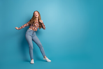 Full size photo of nice young girl dancing empty space wear top isolated on blue color background