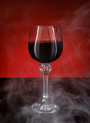 A beautiful glass of red wine surrounded by smoke. Glass with wine on a wooden surface.
