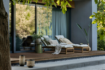 Interior design of warm terrace interior with garden armchair, pillows, vase with flowers, braided...