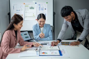 Three people are sitting at a table with papers and graphs in front of them