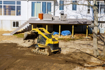 At earthmoving site, tractor is leveling ground during work on backyard construction project